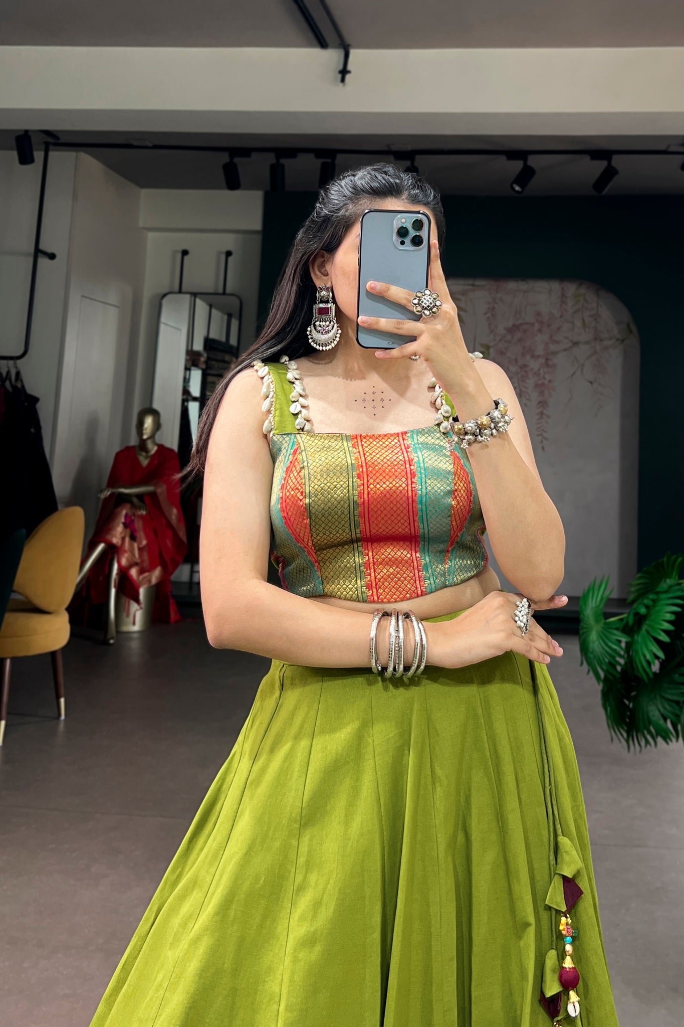 Woman taking a mirror selfie wearing a colorful top and parrot green skirt