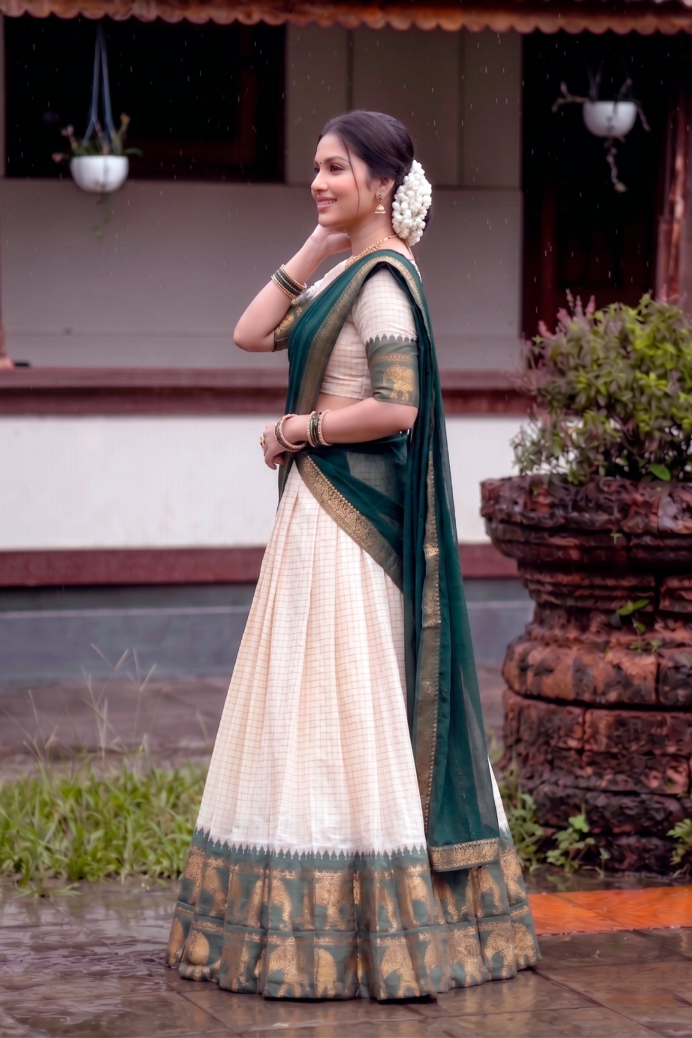 Woman in a green and white lehenga choli standing outdoors.