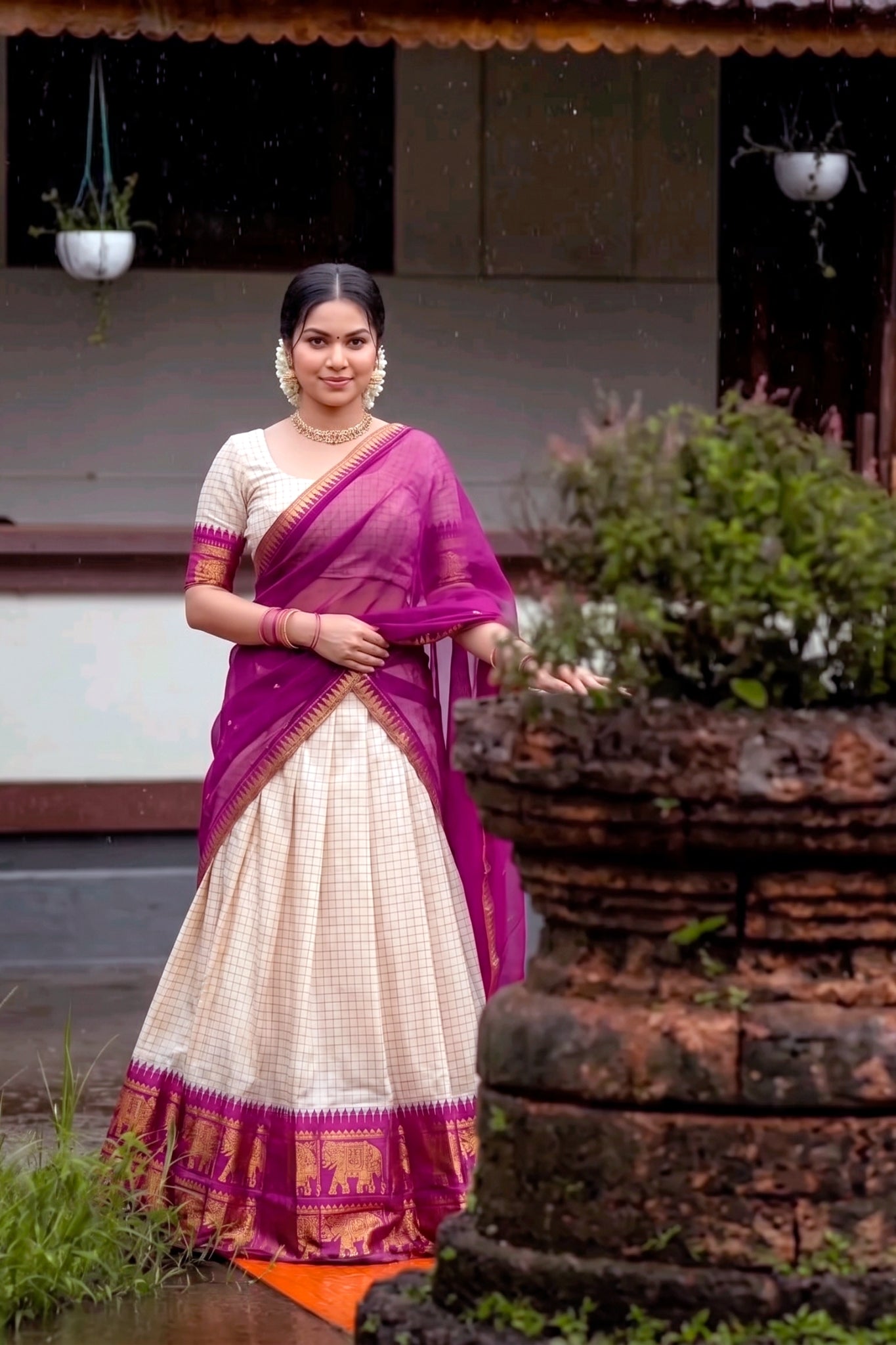 Woman in a wine and white saree standing outdoors 